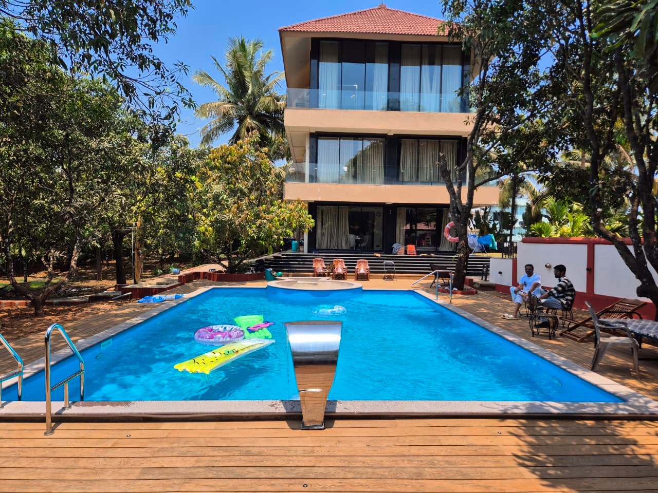 Pool contractor — Goa villa pool with wooden deck and water feature